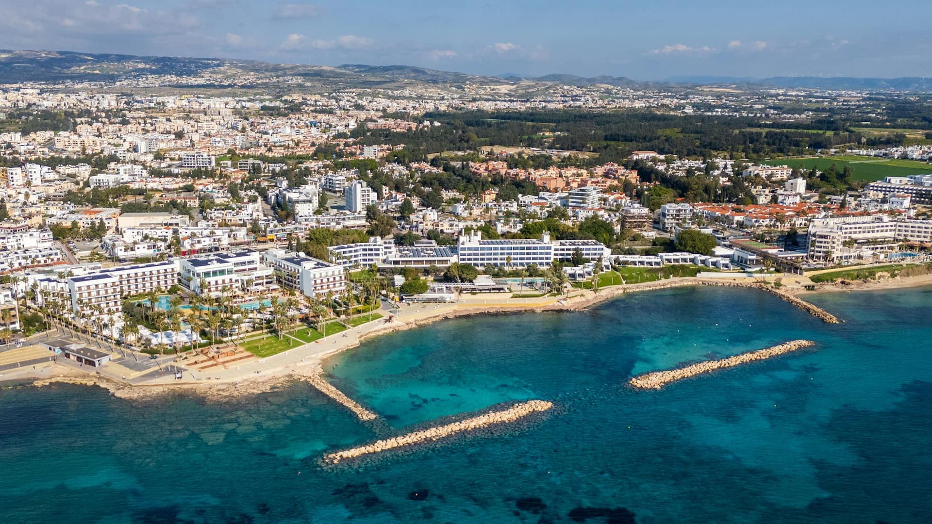 An aerial view of Limassol's business district and coastline, with modern towers and the Mediterranean Sea.