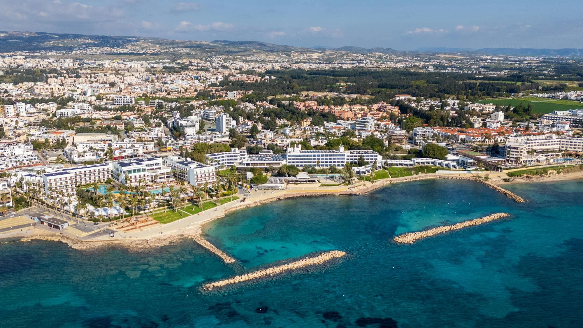 An aerial view of Limassol's business district and coastline, with modern towers and the Mediterranean Sea.